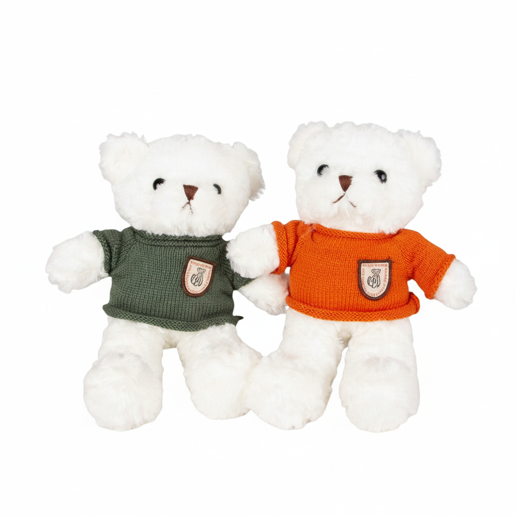 Two white teddy bears wearing green and orange sweaters on a white background