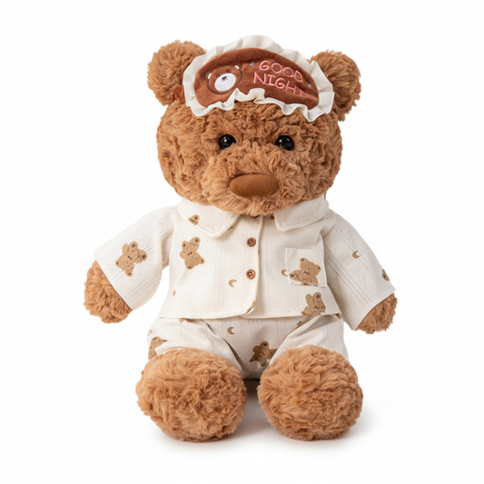 Teddy bear wearing pajamas with a 'Good Night' cap on a white background
